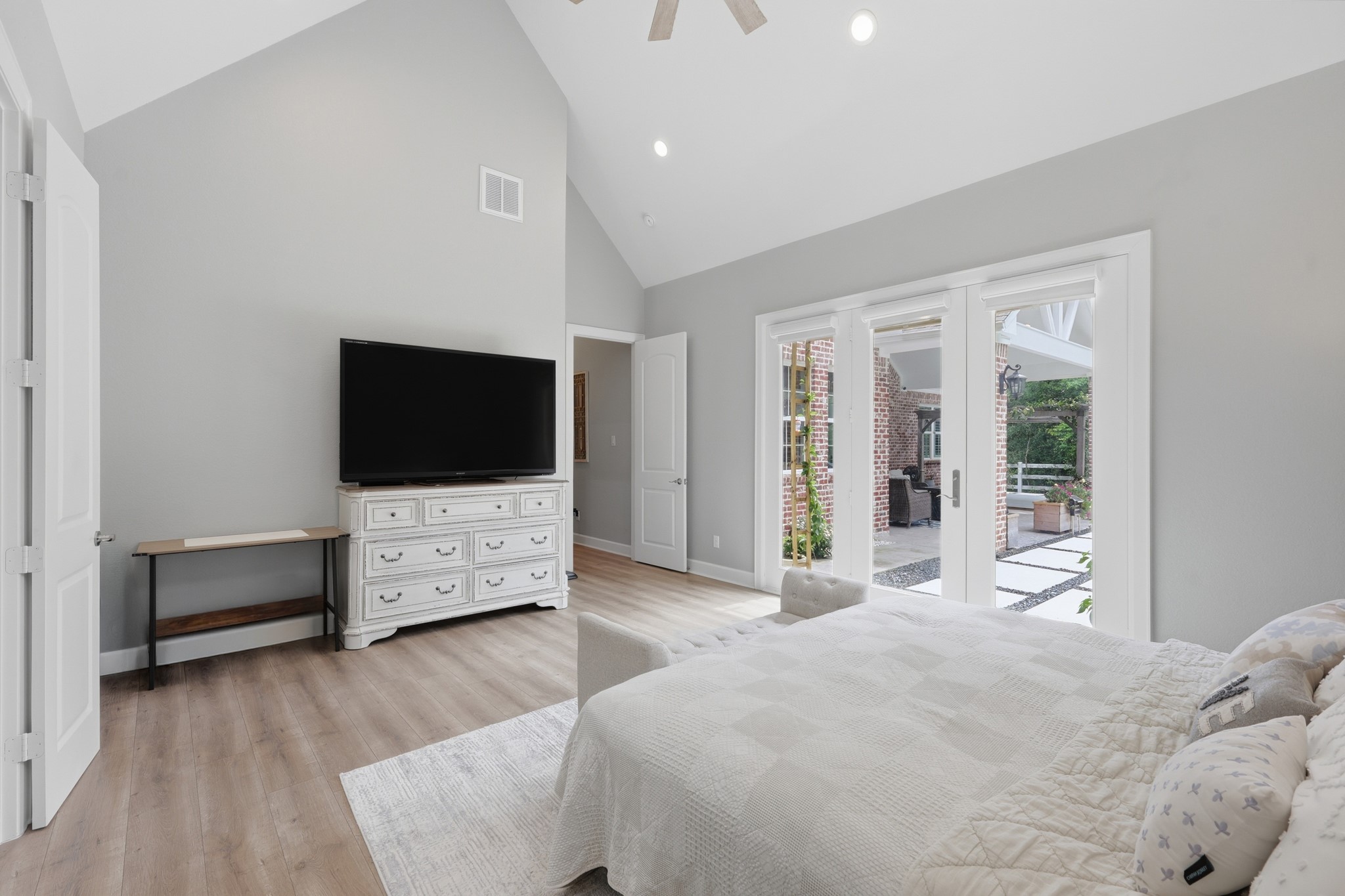 7106 Hampton Court Spring, TX 77389 - Photo 11 of 31 Spacious master bedroom with high ceilings featuring French doors open to a charming patio, providing ample natural light and outdoor access. Neutral tones create a calming ambiance.