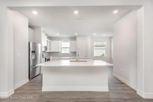 a view of kitchen with kitchen island a sink wooden floor and refrigerator