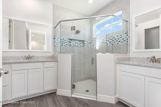 a bathroom with a granite countertop sink a mirror a glass door a shower and vanity