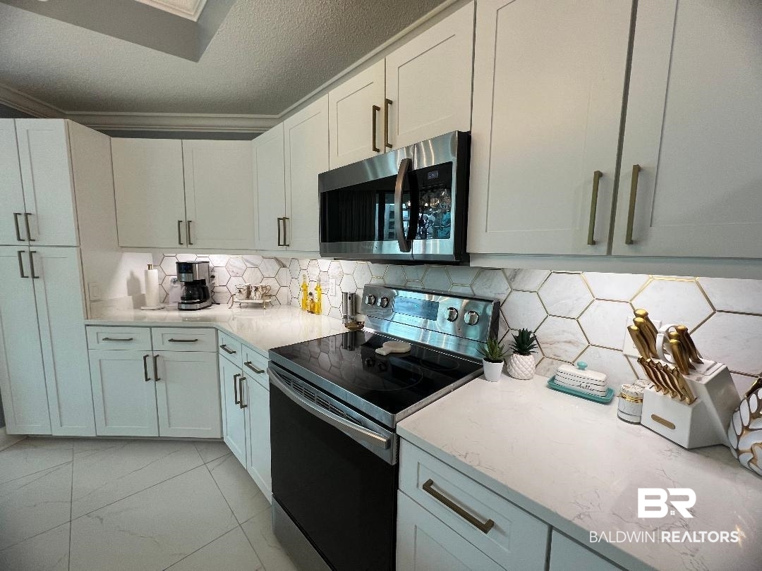 27580 Canal Road, Unit 1210 Orange Beach, AL 36561 - Photo 10 of 28 Kitchen featuring electric range oven, stainless steel microwave, light stone counters, a textured ceiling, and white cabinets