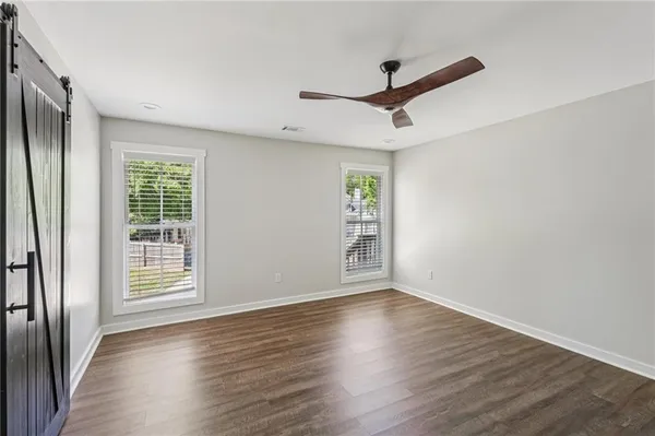 a view of an empty room with wooden floor and a window