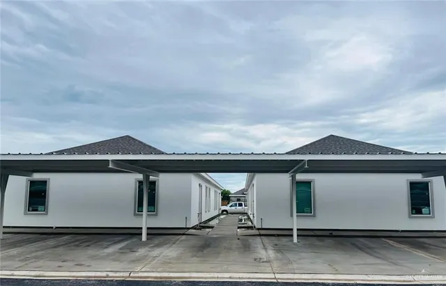 a view of a white house next to a yard