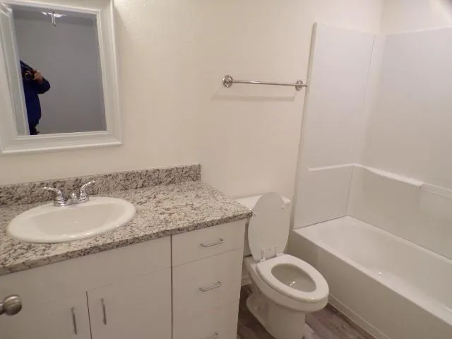 a bathroom with a granite countertop toilet sink and mirror