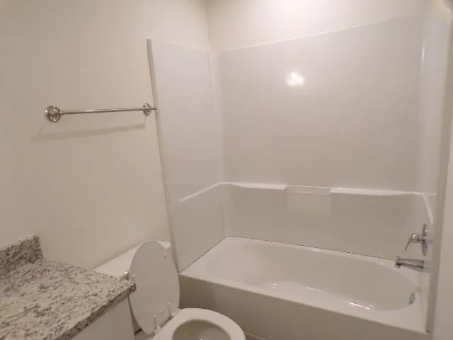 a bathroom with a granite countertop bathtub shower and toilet
