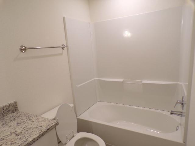 709 South 5th Street, Unit 2 Bonham, TX 75418 - Photo 20 of 32 a bathroom with a granite countertop bathtub shower and toilet