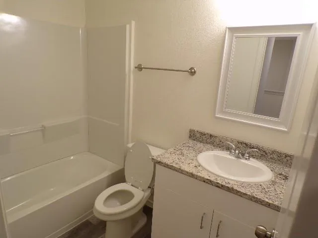 a bathroom with a granite countertop toilet a sink and bathtub
