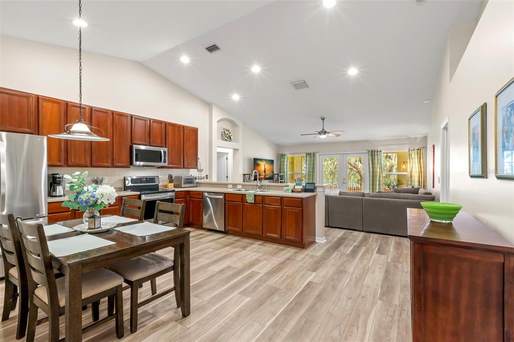 734 Berry Bramble Drive Brandon, FL 33510 - Photo 12 of 49 a kitchen with stainless steel appliances kitchen island granite countertop a refrigerator a sink dishwasher a dining table and chairs with wooden floor