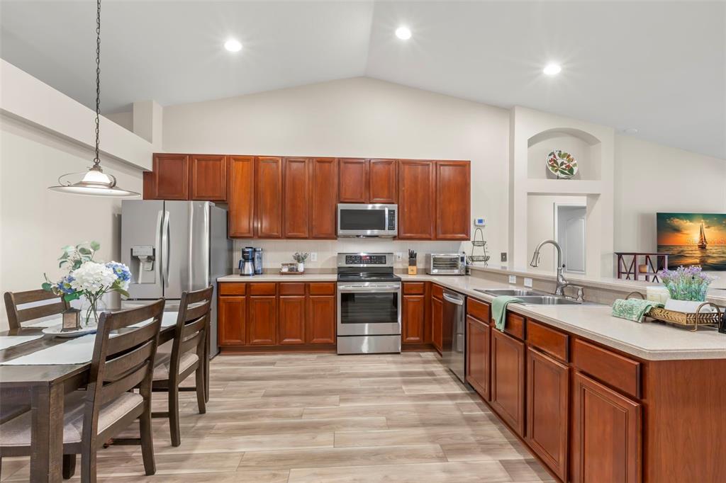734 Berry Bramble Drive Brandon, FL 33510 - Photo 13 of 49 a kitchen with stainless steel appliances granite countertop wooden cabinets a sink a stove a dining table and chairs