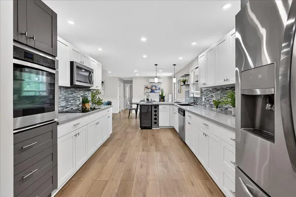 a large kitchen with stainless steel appliances kitchen island granite countertop a stove a sink and a refrigerator