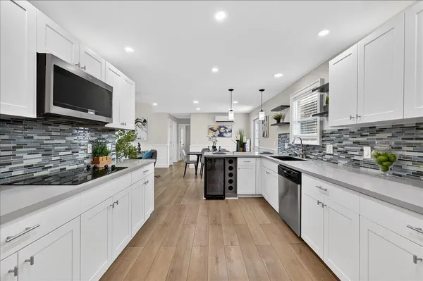 a large white kitchen with stainless steel appliances granite countertop lots of counter top space a sink and cabinets