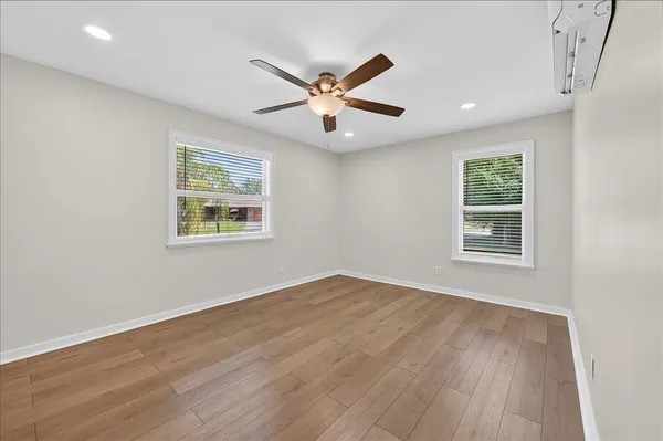 a view of an empty room with wooden floor and a window