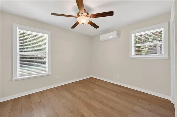 a view of an empty room with wooden floor and a window