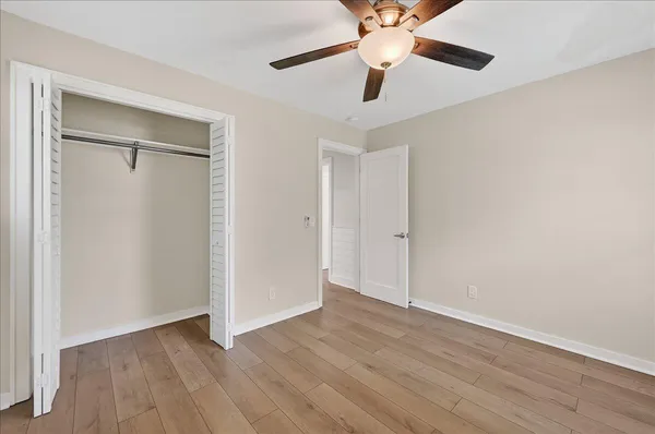 an empty room with wooden floor closet and fan chandelier fan