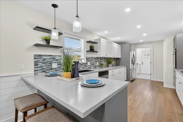 a kitchen with stainless steel appliances granite countertop a sink a stove a dining table and chairs with wooden floor