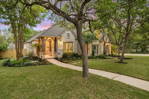 a view of a house with a big yard plants and large trees