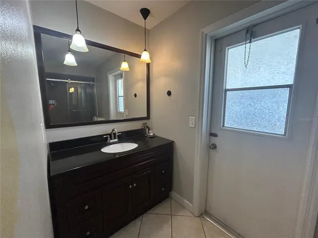 a bathroom with a granite countertop sink a light fixture and a mirror