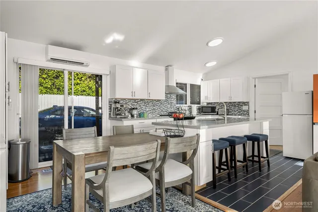 a kitchen with a dining table chairs and refrigerator