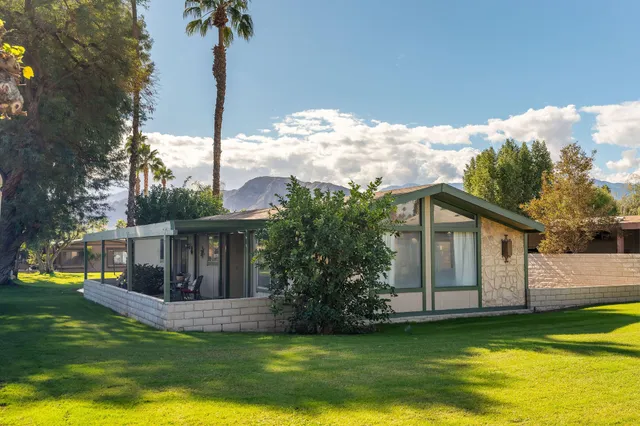 a view of a house with a yard deck and a tree