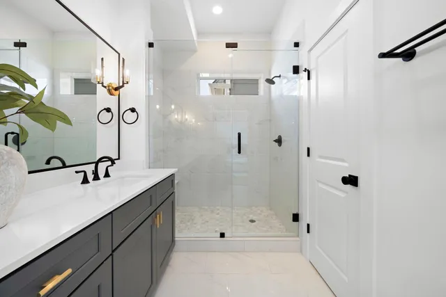 a bathroom with a granite countertop sink a mirror a shower and a bathtub