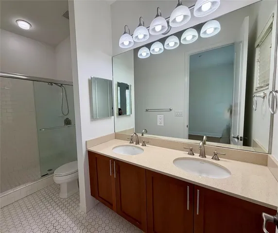 a bathroom with a double vanity sink toilet and a mirror