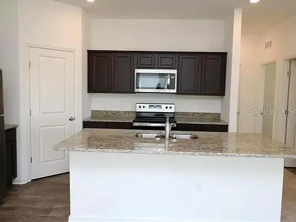 a kitchen with kitchen island granite countertop a stove and a microwave