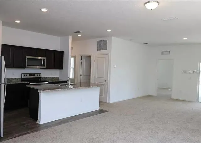 a kitchen with stainless steel appliances a stove top oven a sink a refrigerator and a microwave