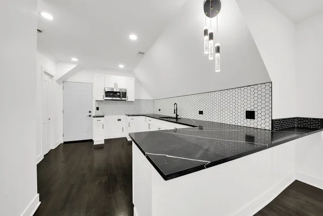 a view of a kitchen with a sink and dishwasher a stove top oven with wooden floor