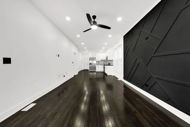 a view of kitchen and empty room with wooden floor