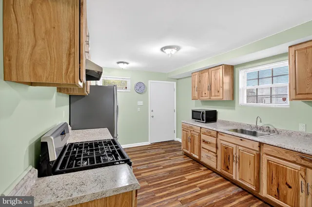 a kitchen with granite countertop a stove a sink and a refrigerator