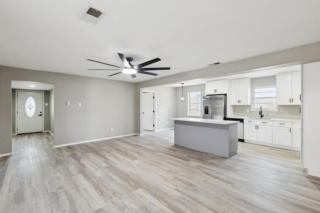 9643 Altacrest Drive Dallas, TX 75227 - Photo 6 of 30 a view of an empty room and kitchen with wooden floor and a window