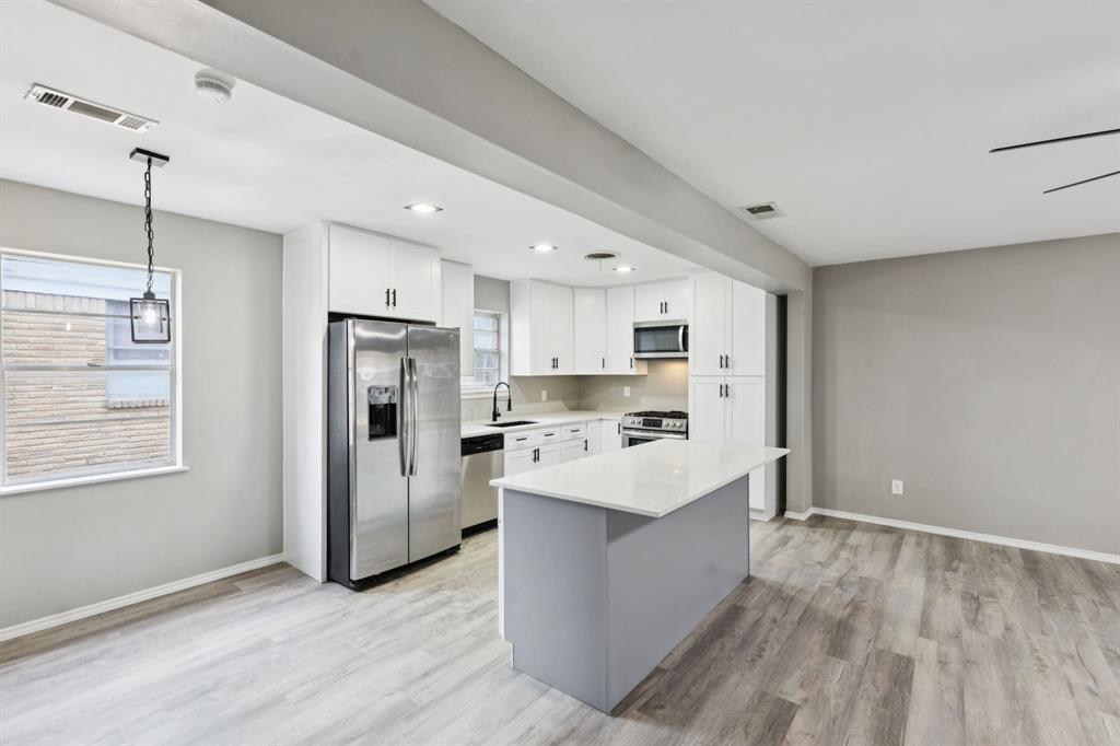 9643 Altacrest Drive Dallas, TX 75227 - Photo 8 of 30 a large kitchen with stainless steel appliances a refrigerator a sink dishwasher a oven with white cabinets and wooden floor