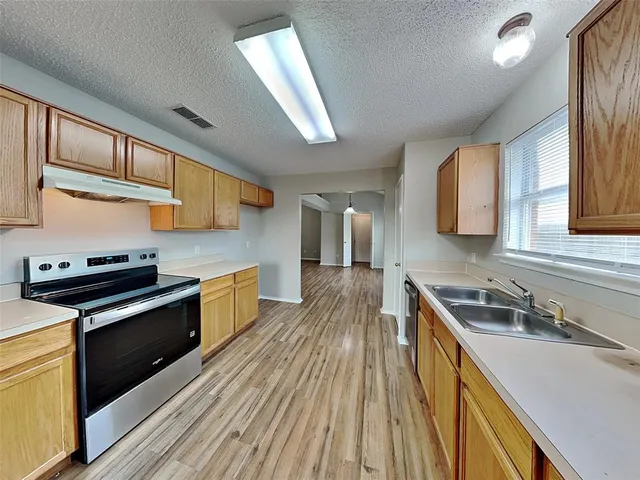 a kitchen with wooden cabinets stove top oven and sink