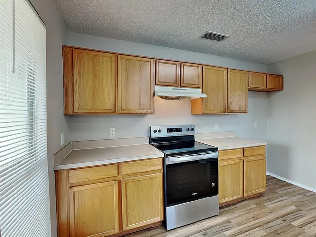 a kitchen with stainless steel appliances granite countertop white cabinets and a stove top oven