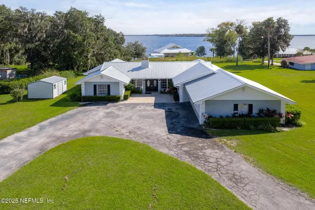 a aerial view of a house next to a big yard with plants and large trees