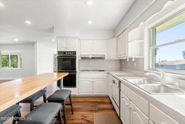 a kitchen with stainless steel appliances granite countertop a table chairs sink and cabinets