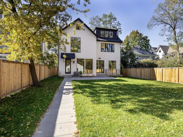 a view of a house with a small yard and a large tree