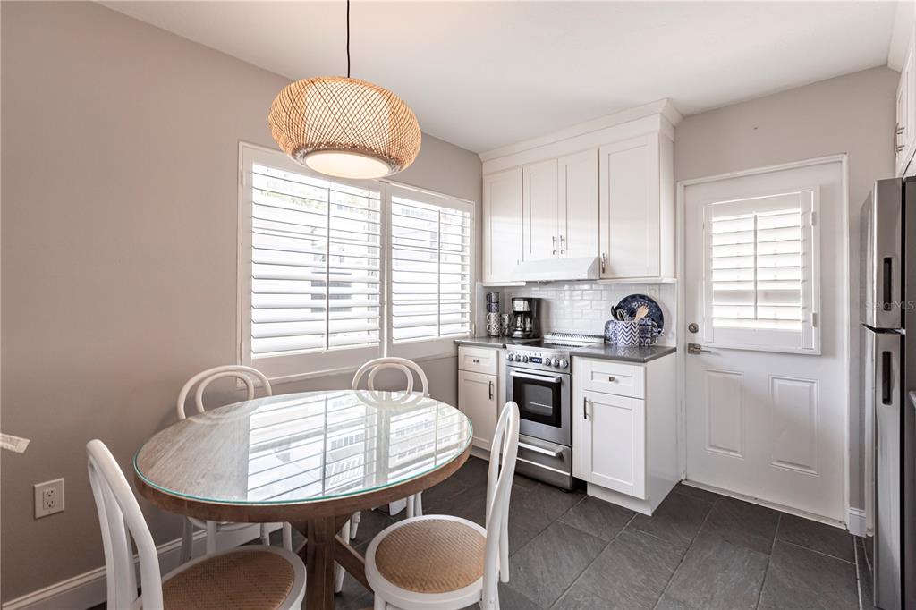 6020 Midnight Pass Road, Unit 31 Sarasota, FL 34242 - Photo 6 of 19 a kitchen with a white appliances a dining table chairs and a window