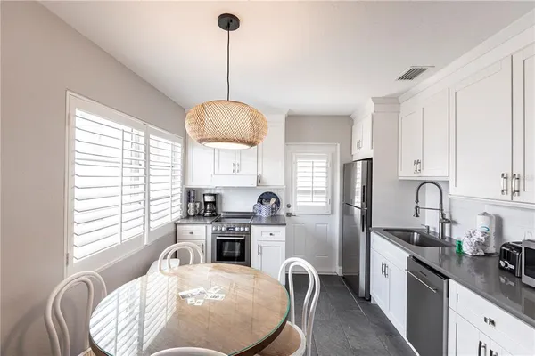 a kitchen with stainless steel appliances granite countertop a refrigerator a sink dishwasher a stove and white cabinets with wooden floor