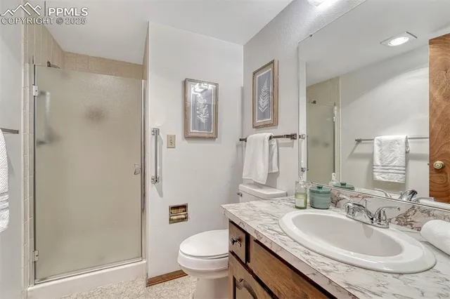a bathroom with a granite countertop sink a toilet a mirror and shower