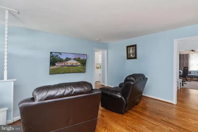 a living room with couches and a flat screen tv with wooden floor