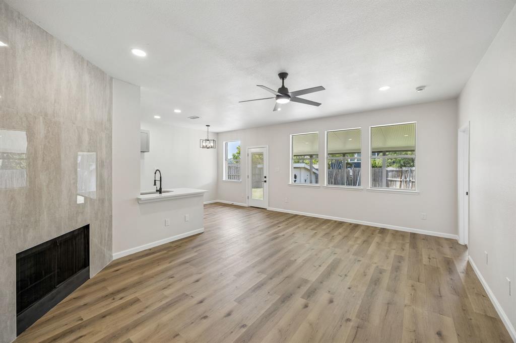 13347 Dove Ranch Road Fort Worth, TX 76262 - Photo 3 of 30 Open-concept living space featuring wood-finish flooring, a tiled fireplace, recessed lighting, and a contemporary ceiling fan