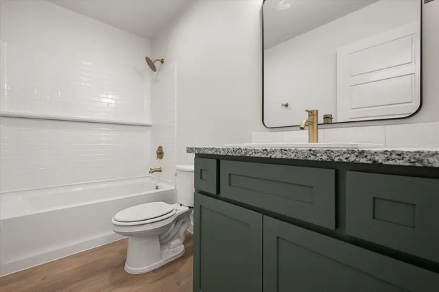 a bathroom with a granite countertop toilet sink and mirror