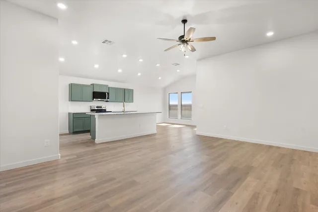 a view of kitchen with microwave a stove and white cabinets