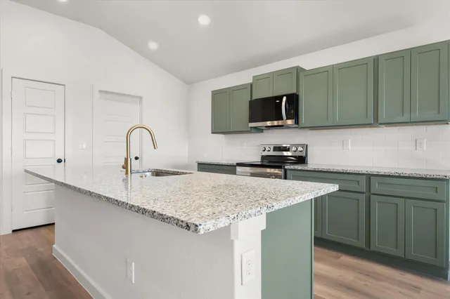 a kitchen with a sink and a stove top oven with wooden floor