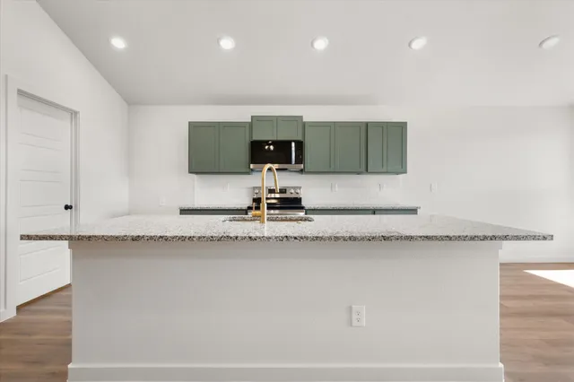 a kitchen with granite countertop a sink a stove and a granite counter top