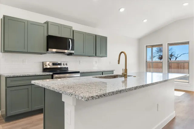 a kitchen with granite countertop a sink and a stove top oven with wooden floor