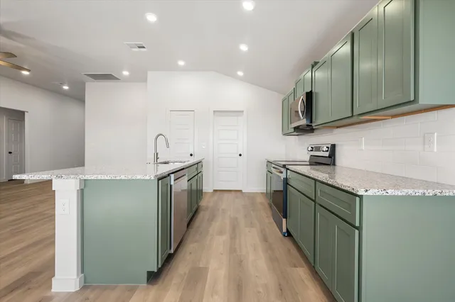 a kitchen with stainless steel appliances granite countertop a sink and a stove top oven