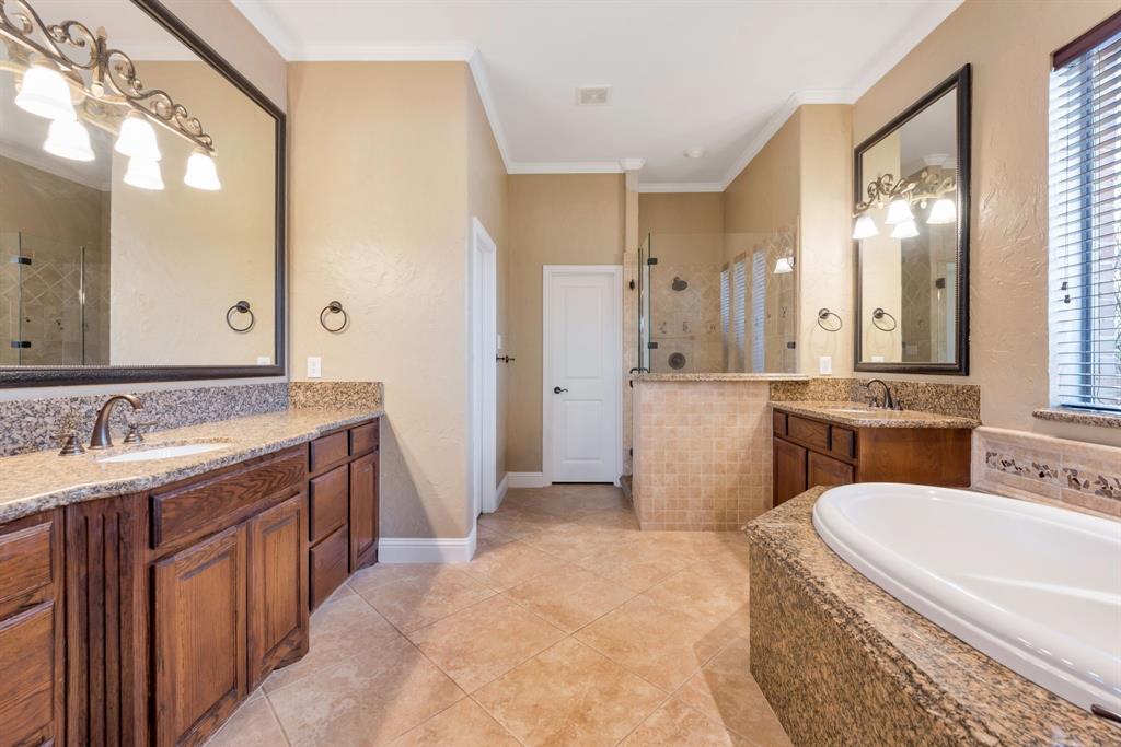 701 Buffalo Springs Drive Prosper, TX 75078 - Photo 11 of 15 a bathroom with a granite countertop double vanity sink a mirror a bathtub and shower