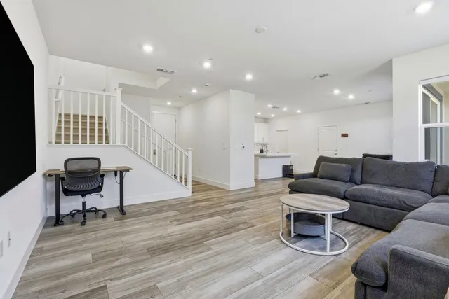 a living room with furniture a flat screen tv and a floor to ceiling window