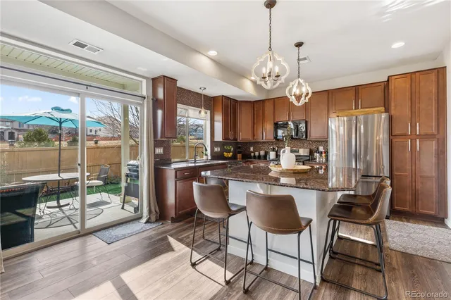 a kitchen with stainless steel appliances granite countertop a stove a refrigerator a kitchen island a table and chairs